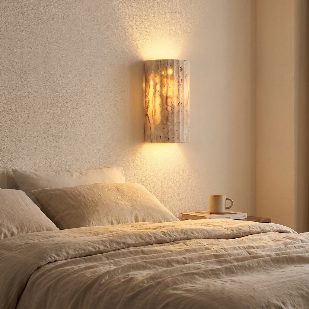 Natural stone sconce glowing beside a bed